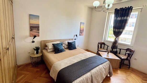 Een slaapkamer met een bed, nachtkastje, stoel en kunstwerken aan de wanden.