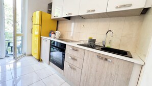 Een moderne keuken met een gele koelkast, een zwarte vaatwasser en een gootsteen met een kraan.