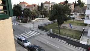 Een straatbeeld met geparkeerde auto's langs de kant, een zebrapad en gebouwen op de achtergrond.