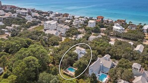 An aerial view of a coastal residential area with houses, a swimming pool, and a clear view of the ocean. - Beach Baby - Secluded Home with Private Pool Area & Deck (Santa Rosa Beach)