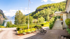 A scenic view of a mountain with a lake, a flag, and a building with steps leading to a door. - Heimly (Aurland)