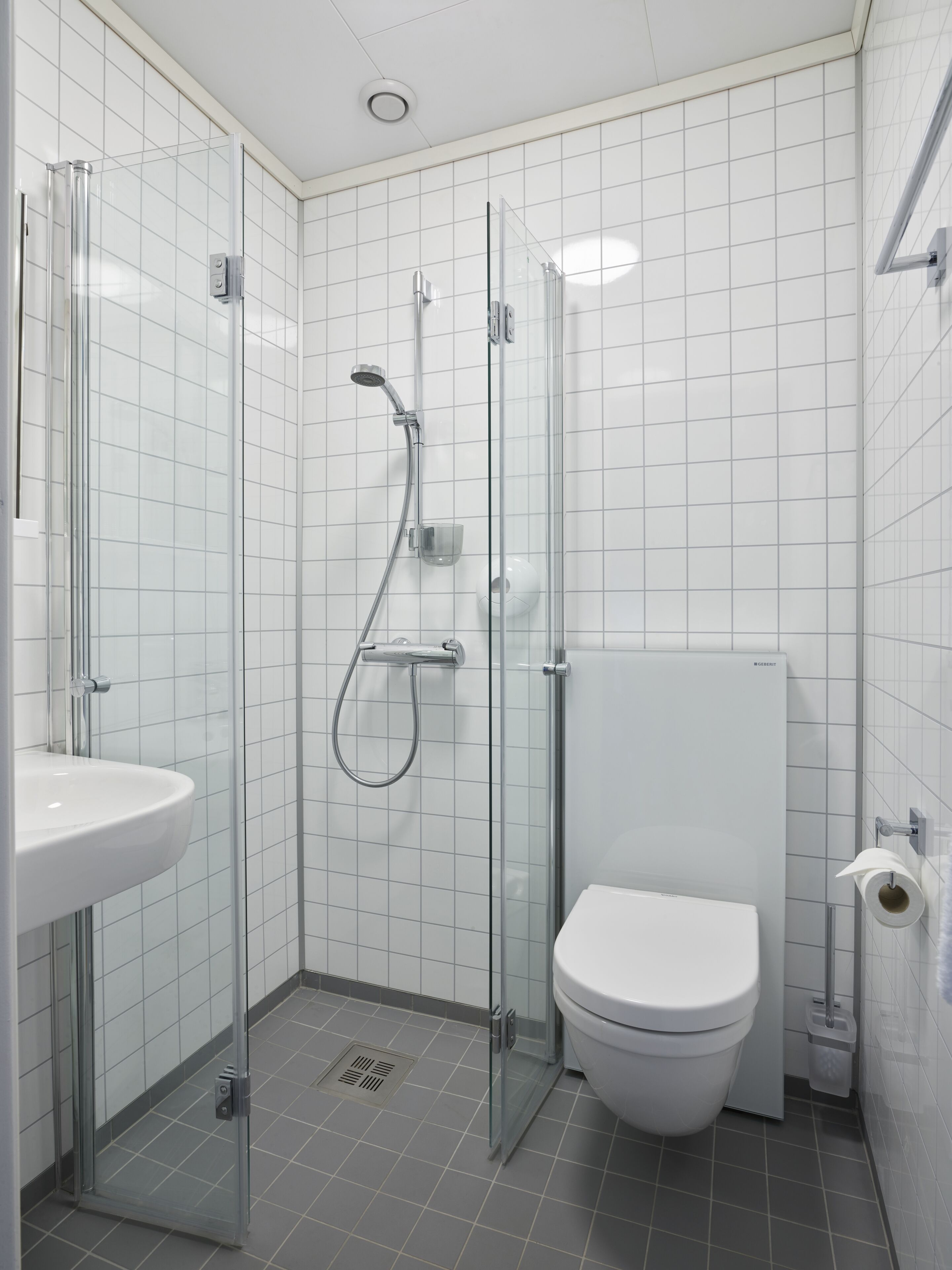 Une salle de bain moderne avec une douche à parois de verre, des toilettes blanches et un lavabo.