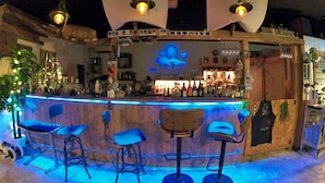 Un bar amb un taulell de fusta, diverses solles altes i llums penjants.