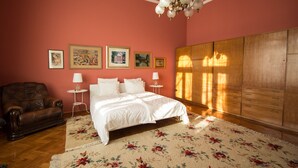 A bedroom with a bed, a wooden wardrobe, a leather sofa, and a chandelier. - Kaptol Residence (Zagreb)