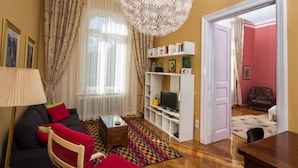 A living room with a sofa, armchair, coffee table, TV stand, and bookshelf. - Kaptol Residence (Zagreb)