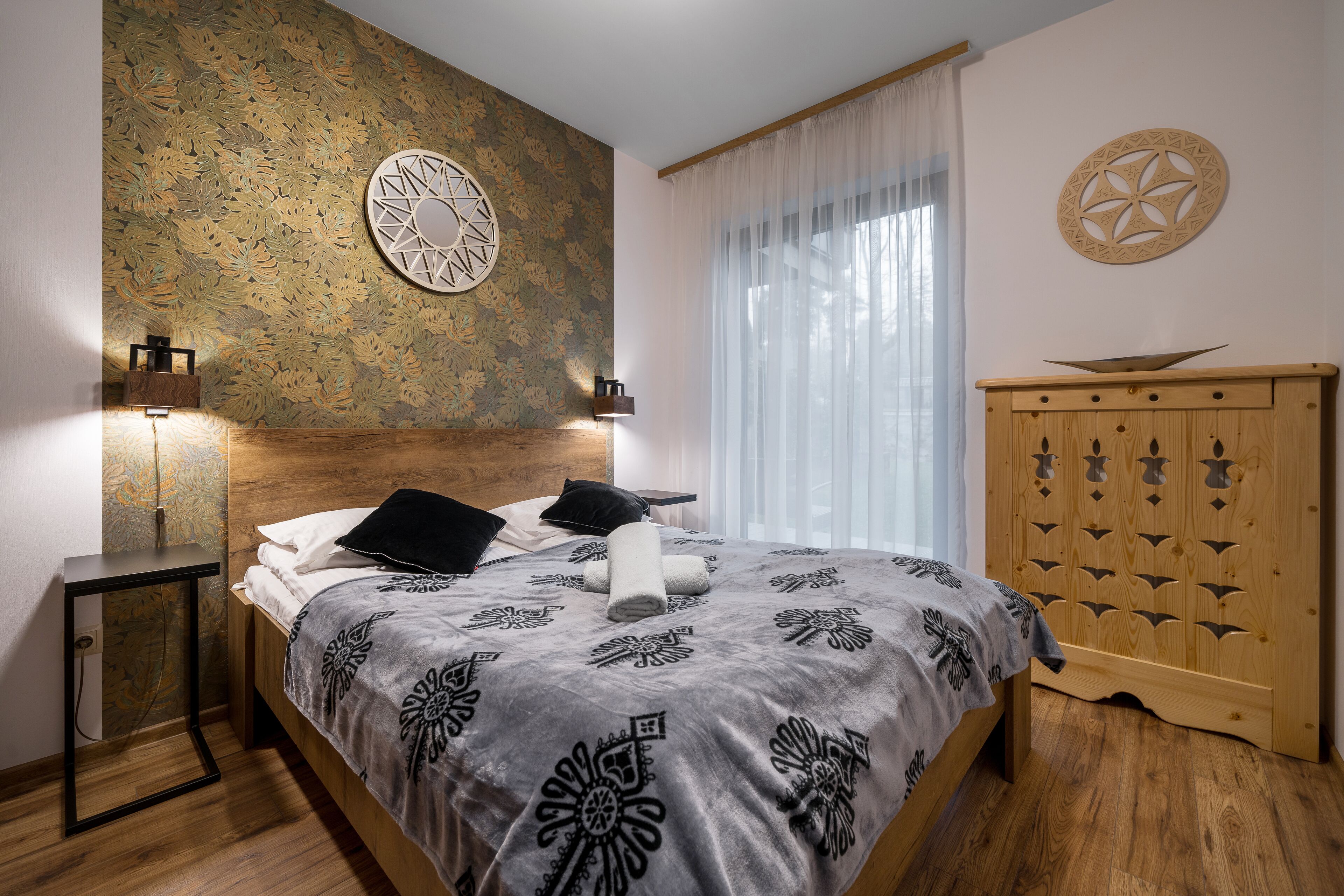 A bedroom with a bed, a nightstand, a wardrobe, and decorative wall art.