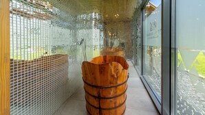 A corridor with a wooden barrel-shaped bench, glass walls, and a tiled floor. - RentPlanet - Apartament Goszczyńskiego (Zakopane)