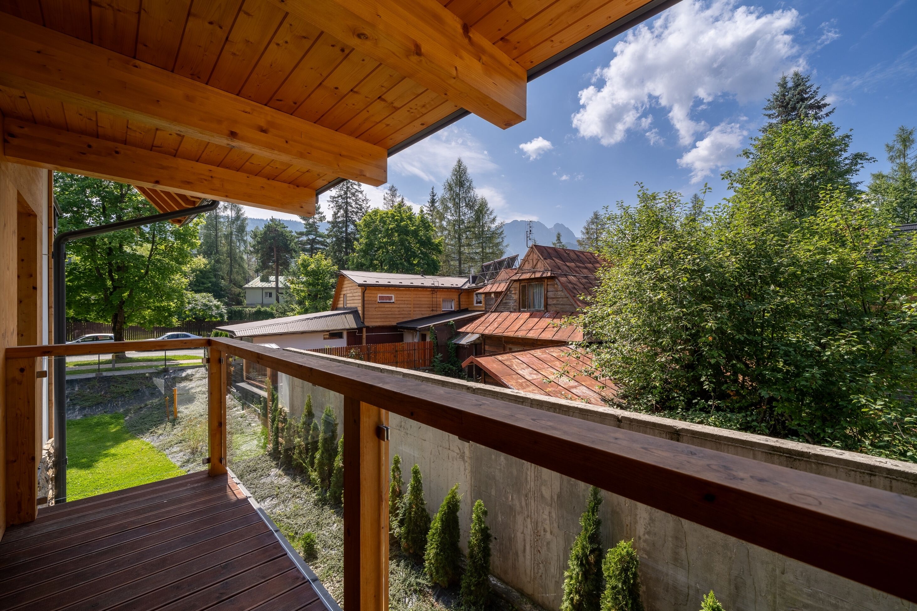 Un balcón de madera con vista a una zona residencial, con casas y árboles.