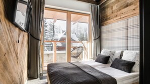 A bedroom with a large bed, wooden walls, and a view of the outside. - RentPlanet - Apartament Goszczyńskiego (Zakopane)
