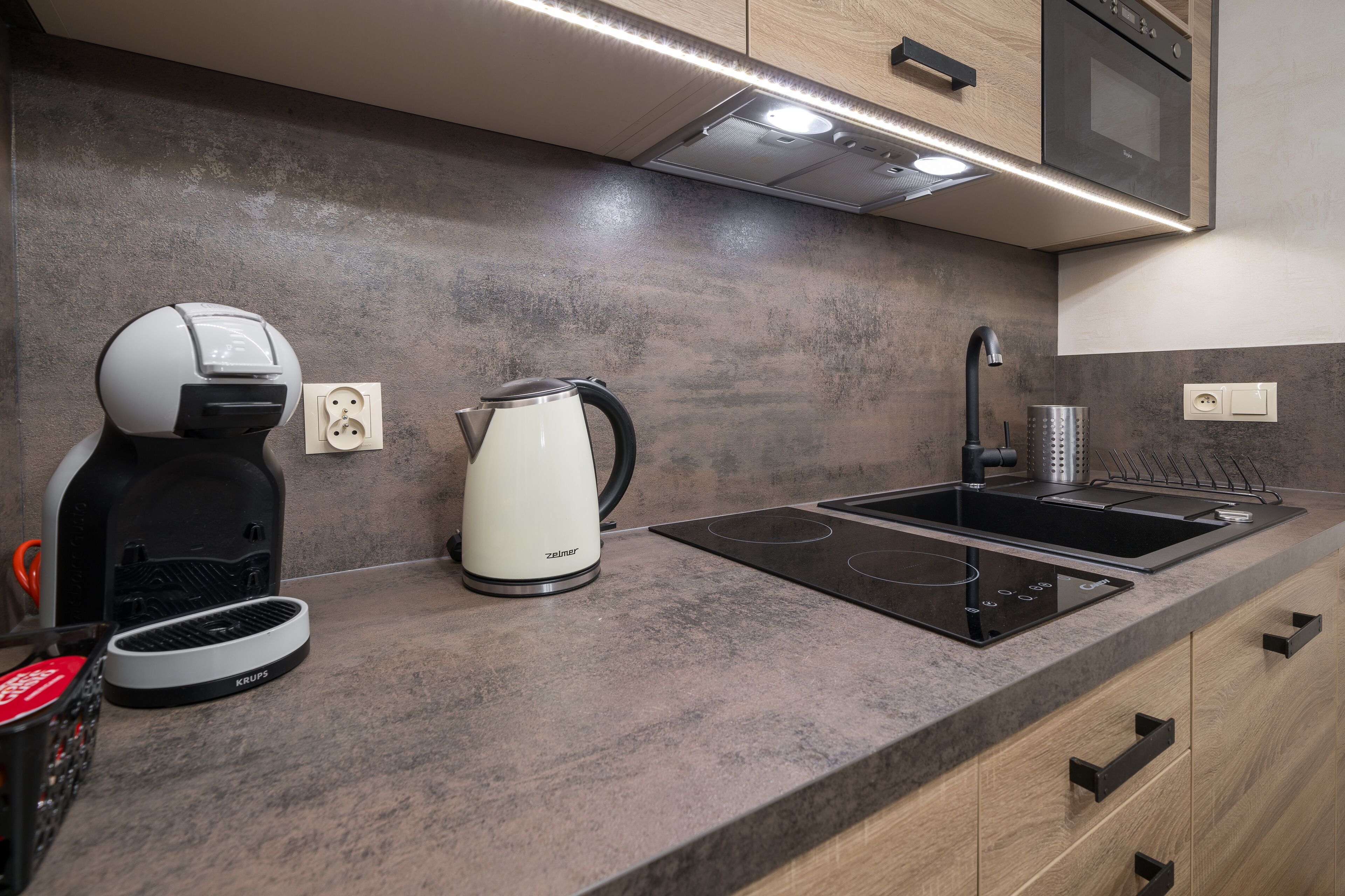 Une cuisine moderne équipée d’une cuisinière intégrée, d’une bouilloire et d’une machine à café.