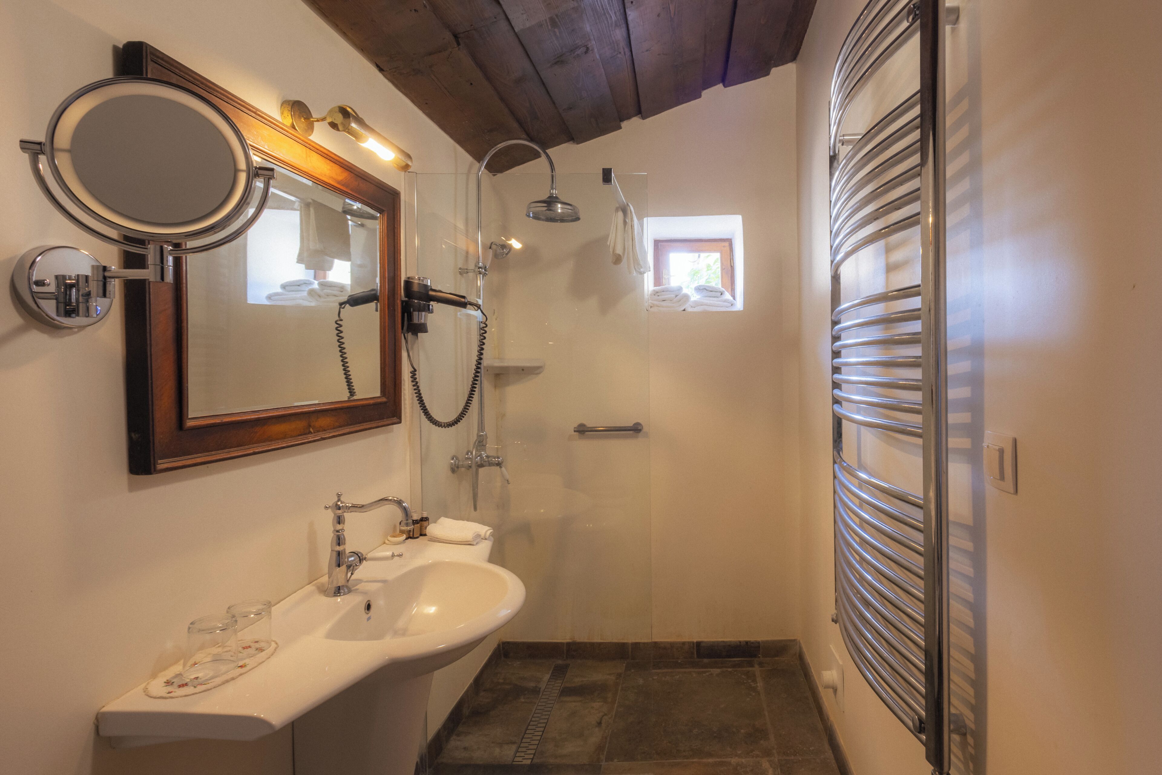 A bathroom with a sink, mirror, shower, and towel rack.