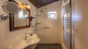 A bathroom with a sink, mirror, shower, and towel rack.