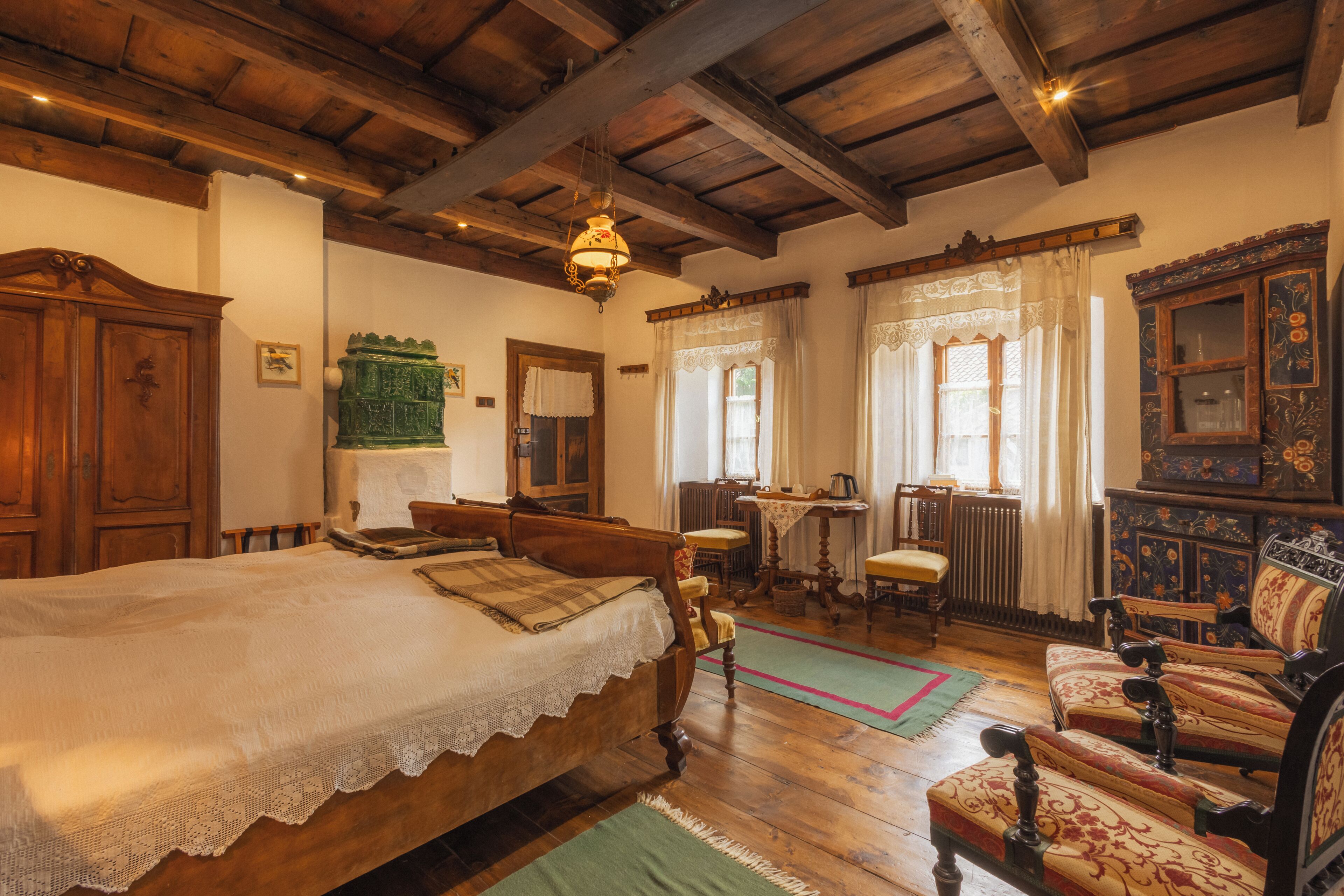A traditional room with a wooden bed, a green sofa, and a wooden cabinet.
