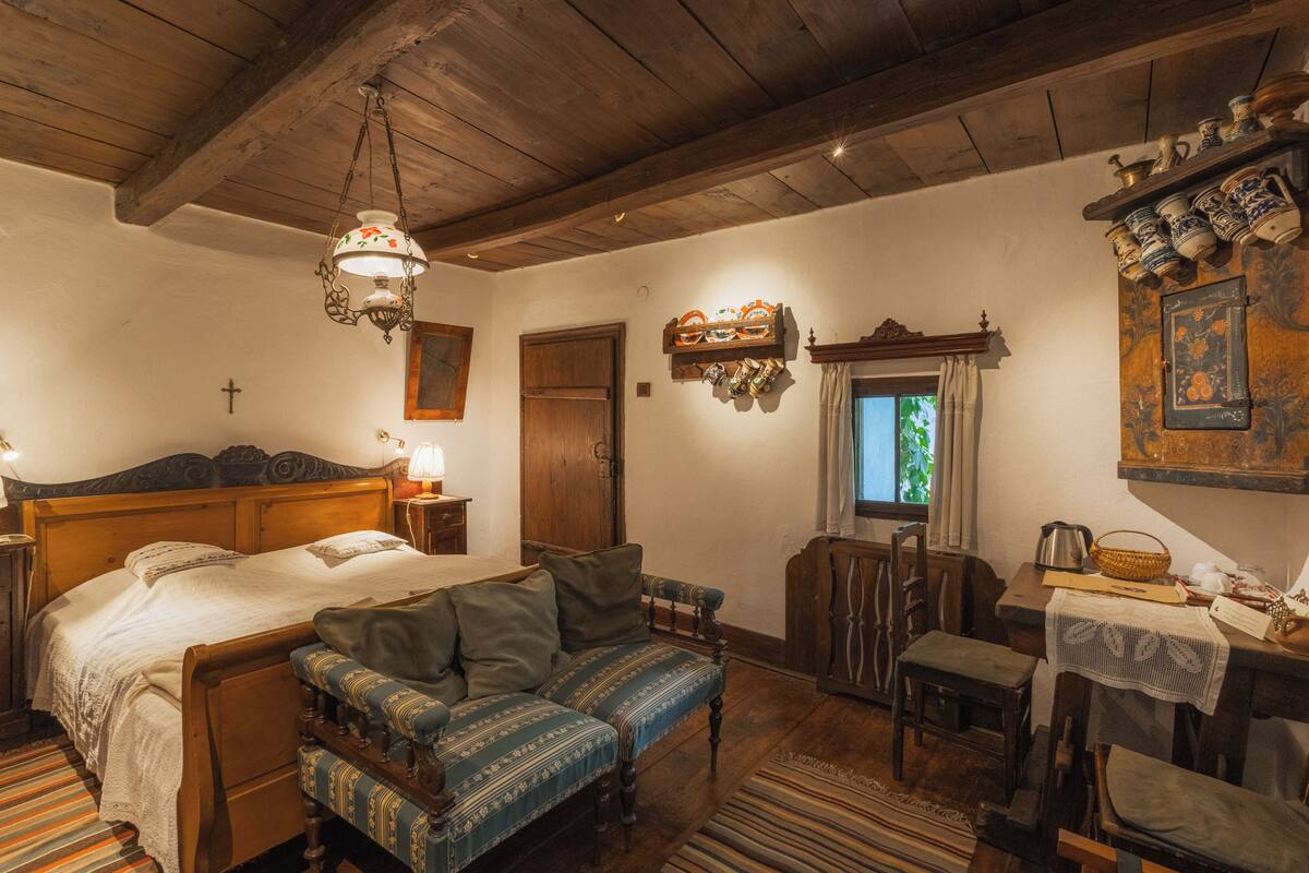 Une chambre traditionnelle avec un lit en bois, un canapé, une table à manger et un lustre.