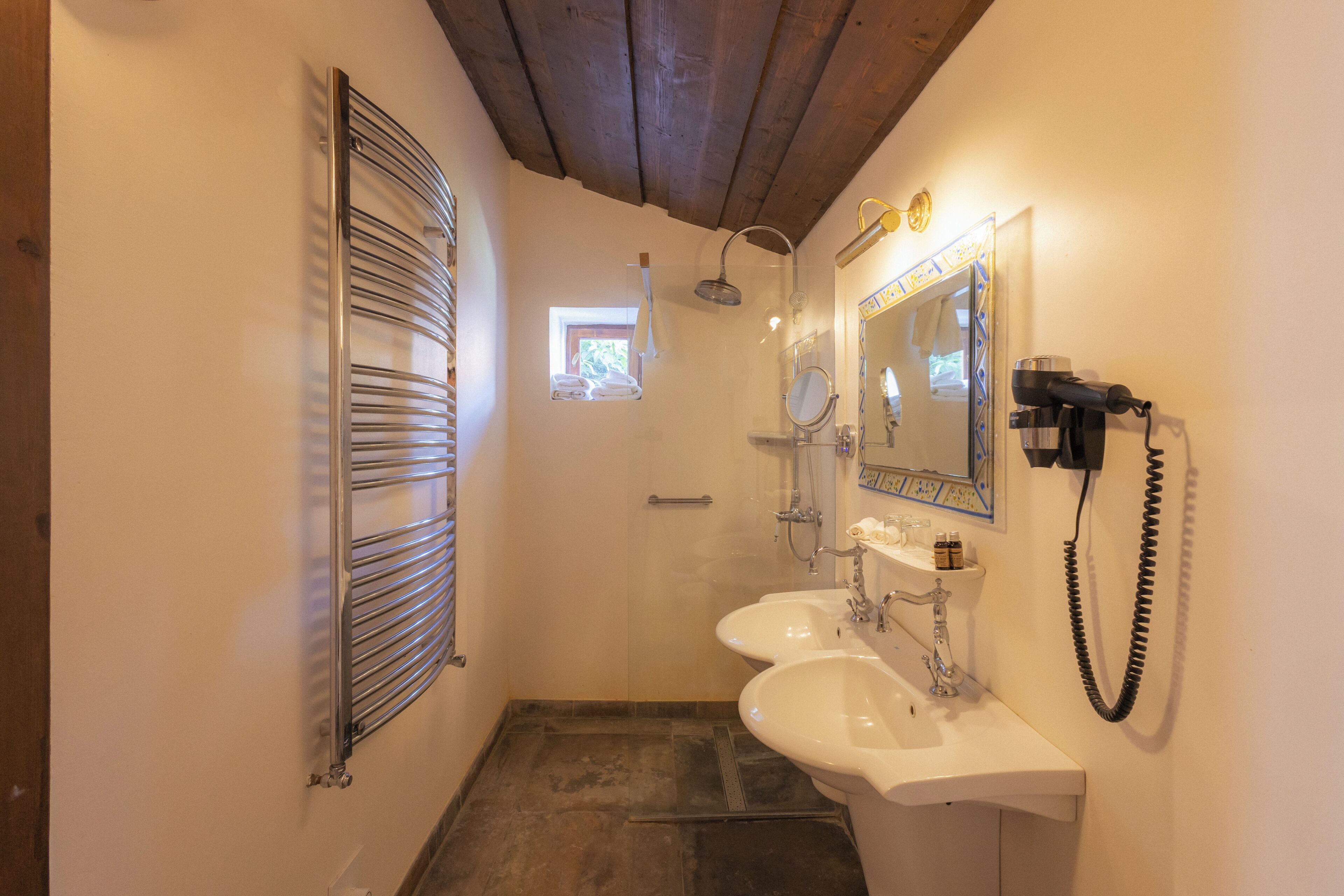 Ein Badezimmer mit Dusche, zwei Waschbecken, einem Spiegel und einem Föhn.