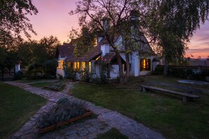 A house with a stone pathway leading to the entrance, surrounded by a garden and a bench. - Count Kalnoky's Transylvanian Guesthouse (Baraolt)