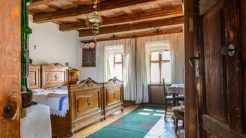 Una habitación tradicional con muebles de madera, una alfombra verde y techo de madera.