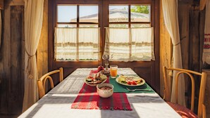 Una cabaña de madera con una mesa de comedor dispuesta para el desayuno, que incluye diversos alimentos y un vaso de jugo de naranja.