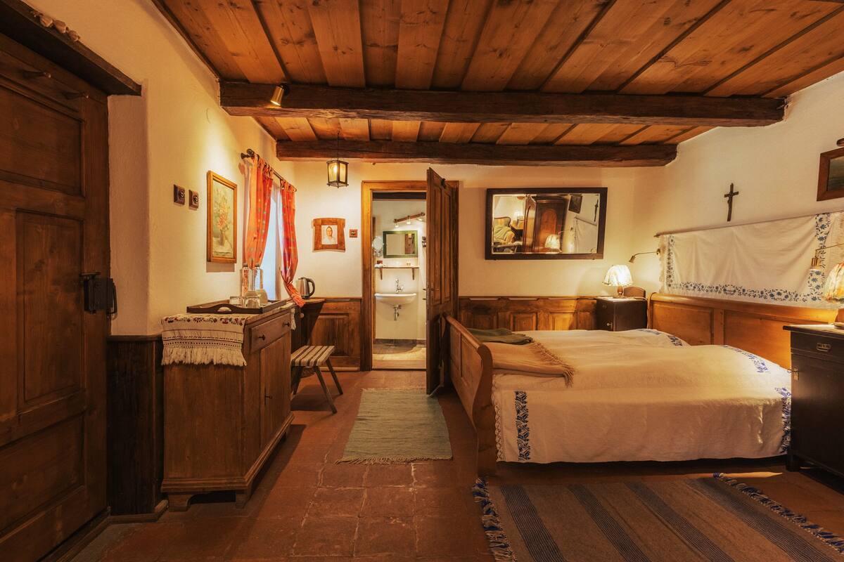 Une chambre traditionnelle avec des poutres en bois, un lit, un bureau et un miroir.
