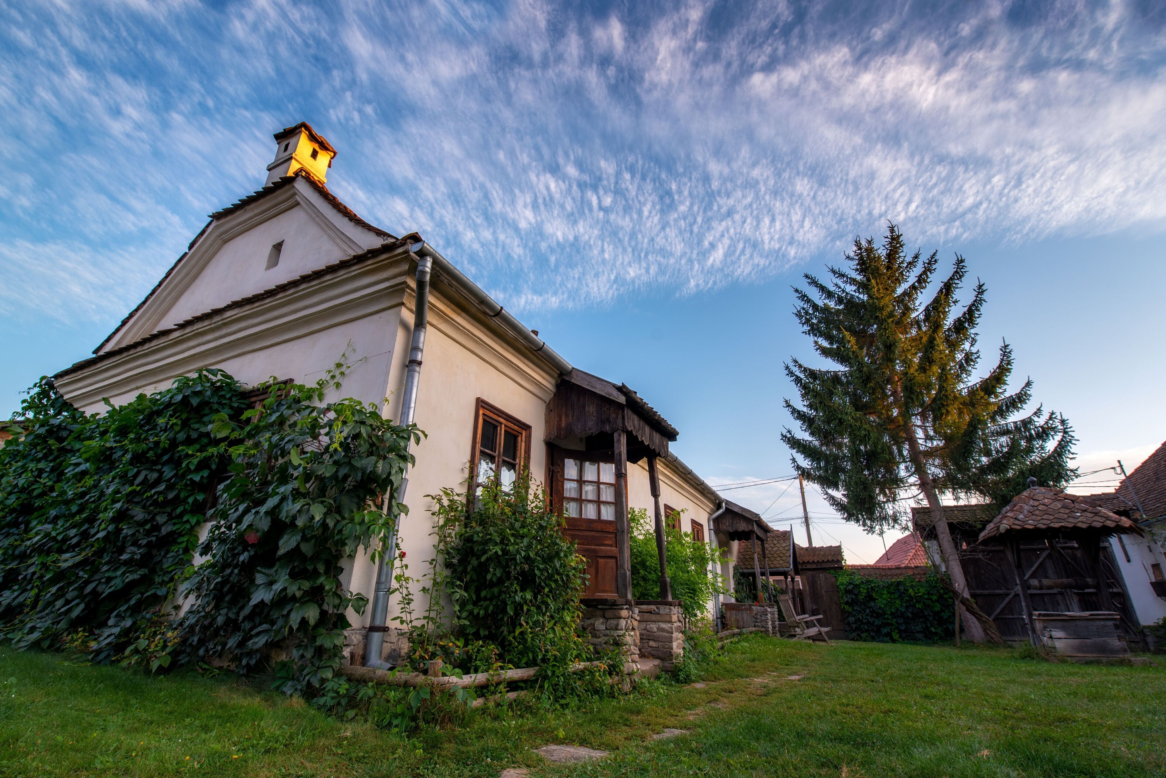 A traditional house with a sloped roof, wooden window frames, and a chimney.