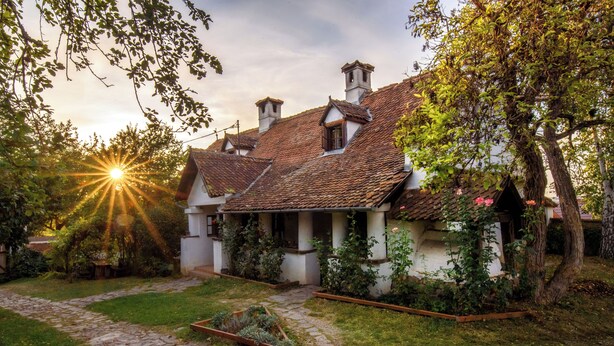 Una casa tradicional con un camino de piedra, un jardín y un cielo despejado.