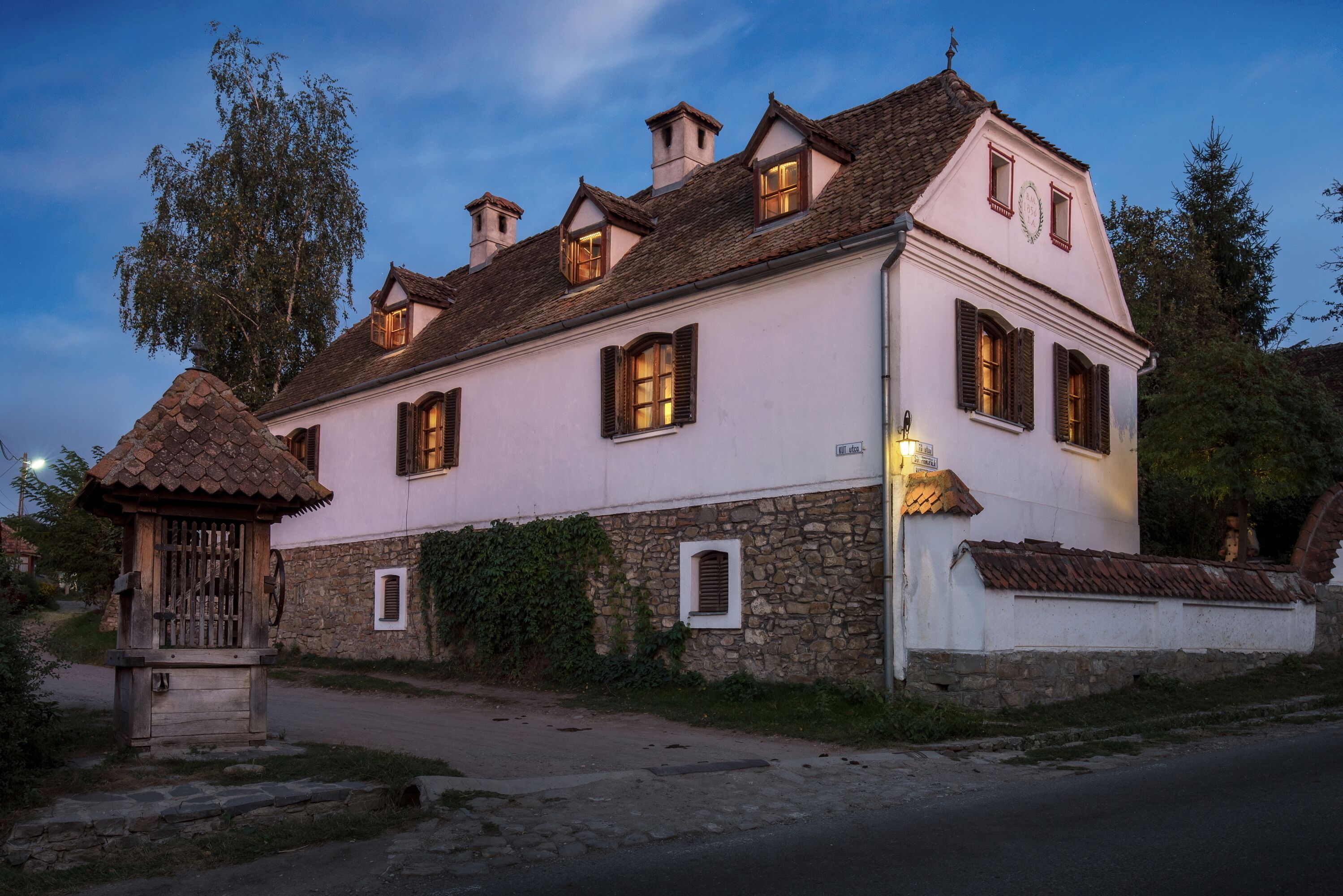Ett traditionellt hus i två våningar med en grund av sten och en rosa överdel, med flera skorstenar och en liten tillbyggnad med ett tak täckt av tegelpannor.