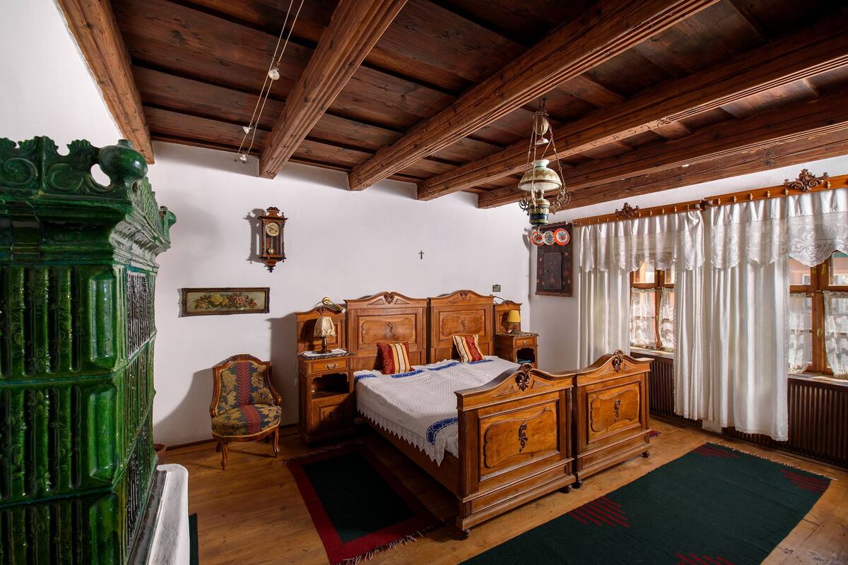 Une chambre traditionnelle avec un lit en bois, une commode verte sculptée et un plafond en bois de style classique.