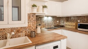 A modern kitchen with white cabinets, a wooden countertop, and patterned backsplash tiles. - Explore Athens with 2 Bedroom Condo (Athens)