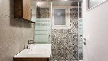 Un baño con un lavabo blanco, un armario de madera, un espejo y baldosas estampadas.