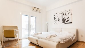 A bedroom with a bed, a desk, and a chair. There is a window and a door. - Explore Athens with 2 Bedroom Condo (Athens)