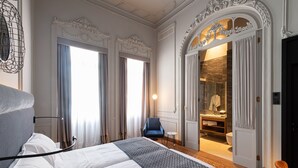 A hotel room with a large bed, a chair, and a bathroom visible through an open door. - Boutique Hotel Cordial Malteses (Las Palmas de Gran Canaria)