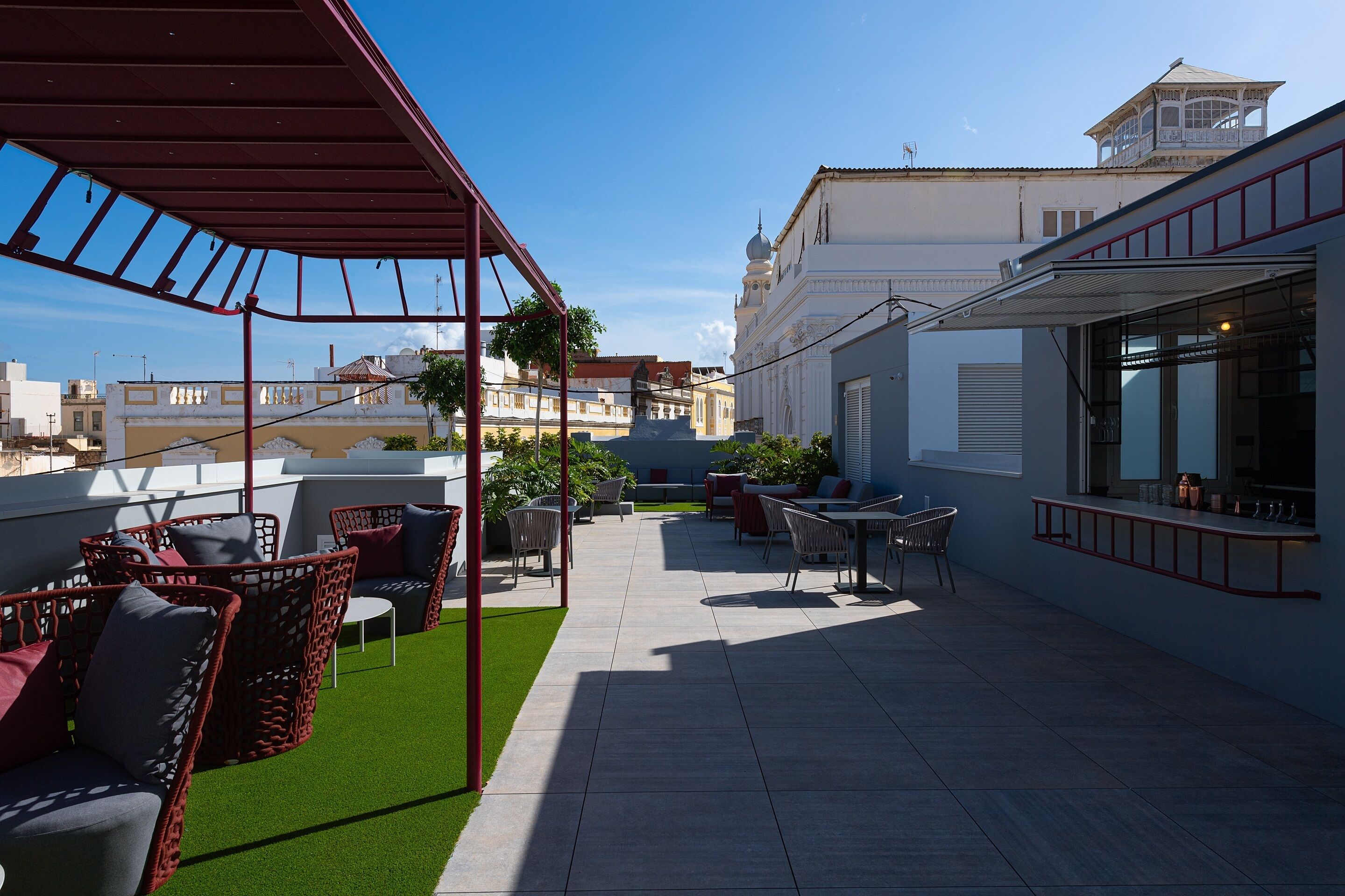 A rooftop terrace with outdoor seating, a statue, and a view of buildings.