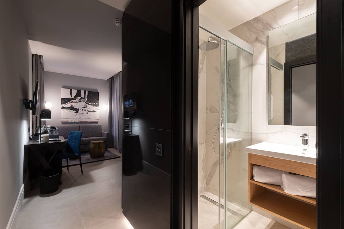 Une salle de bain moderne avec une douche à parois de verre, un lavabo en marbre et un grand miroir.
