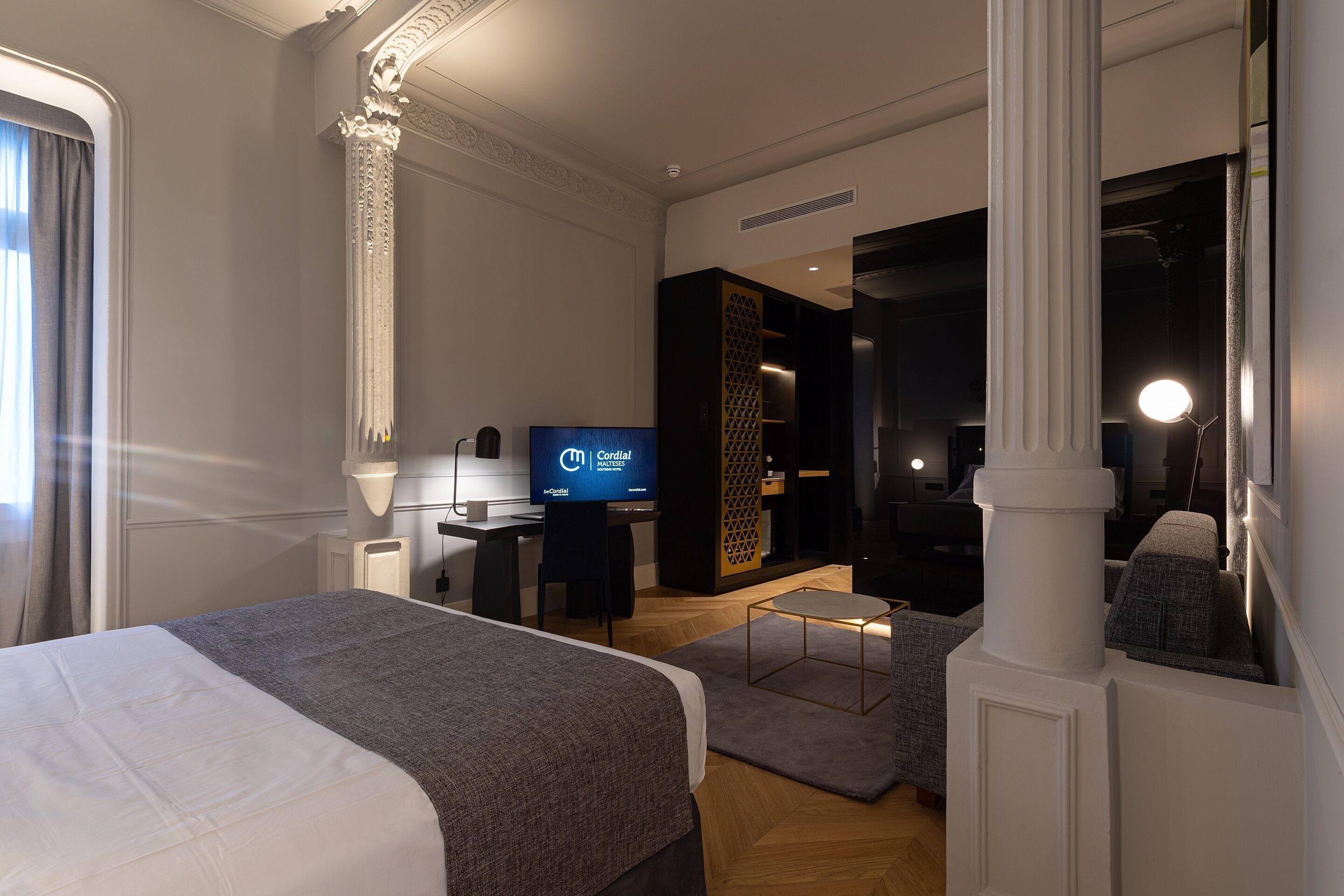 Een hotelkamer met een groot bed, een bureau met een computer, een televisie en een moderne badkamer.