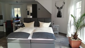 A modern bedroom with a large bed, a desk, and a potted plant. - Comfort apartment in the wildlife park (Koblenz)