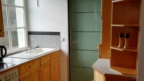 Une cuisine avec des meubles de rangement en bois, un évier, une cuisinière et une porte verte.