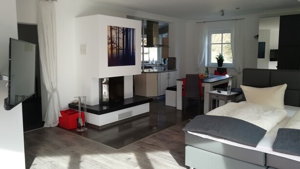 Une chambre d’hôtel moderne équipée d’un grand lit, d’un bureau, d’une kitchenette et d’un téléviseur.