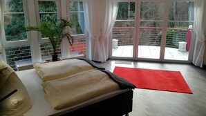 Une chambre à coucher moderne avec un lit, un tapis rouge et de grandes fenêtres avec des rideaux.