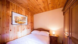 A wooden-paneled room with a bed, a nightstand, and a wardrobe. - Unique Stone House with the charm of past centuries (Herceg Novi)