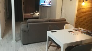 A modern living space with a sofa, a dining table, and a TV mounted on the wall. - YOUR PAUSE IN VALENCIA Center. July and August 10%. Discount (Valencia)