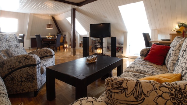 A spacious loft with high ceilings, exposed beams, and large windows. - The Grich (Zagreb)