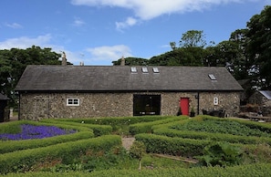 A stone building with a sloped roof, a red door, and a small window.