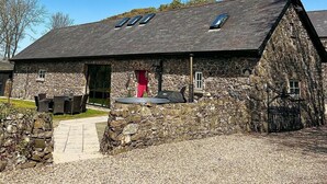 A stone building with a sloped roof, a red door, and a paved entrance. - Unique accommodation in the centre of Bushmills - dating back to 1745  (Bushmills)