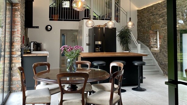 A spacious kitchen with a central island, a dining area with wooden chairs, and a staircase leading to an upper level. - Unique accommodation in the centre of Bushmills - dating back to 1745  (Bushmills)