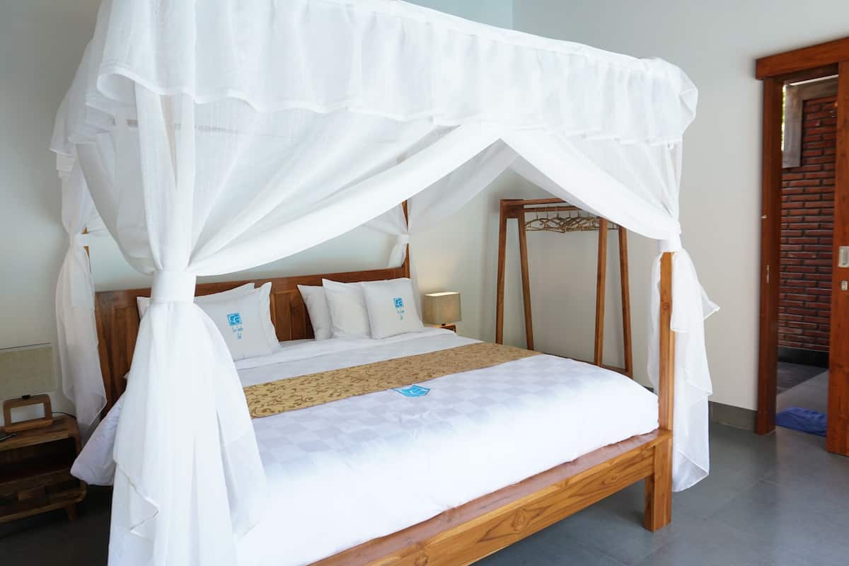Cama com dossel, cabeceira de madeira e colcha com logotipo.