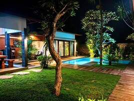 A modern house with a swimming pool, a patio, and a well-maintained lawn.