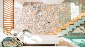 A modern room with a stone wall, a wooden staircase, and a pool. - Villa Lydia (Kissamos)