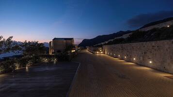 A wooden pathway leading to a building with stone walls, under a twilight sky.