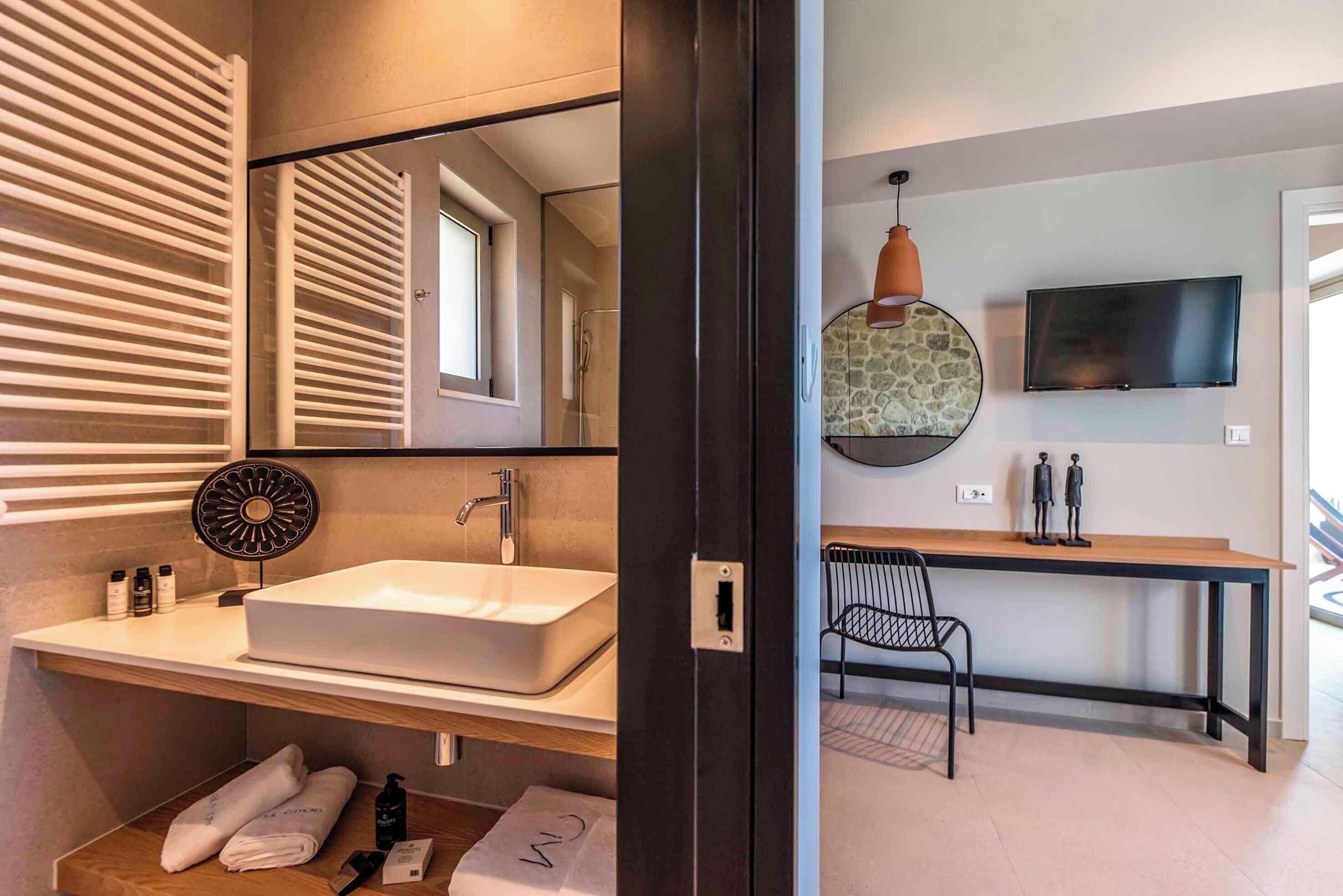 A modern bathroom with a large mirror, a white sink, and a towel rack.