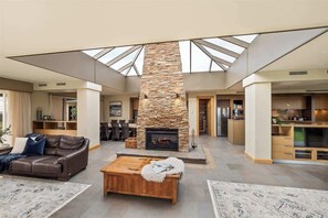 A spacious living area with a stone fireplace, a wooden coffee table, and a leather sofa. - Incognito—An Exclusive Oceanfront Estate (Gracetown)